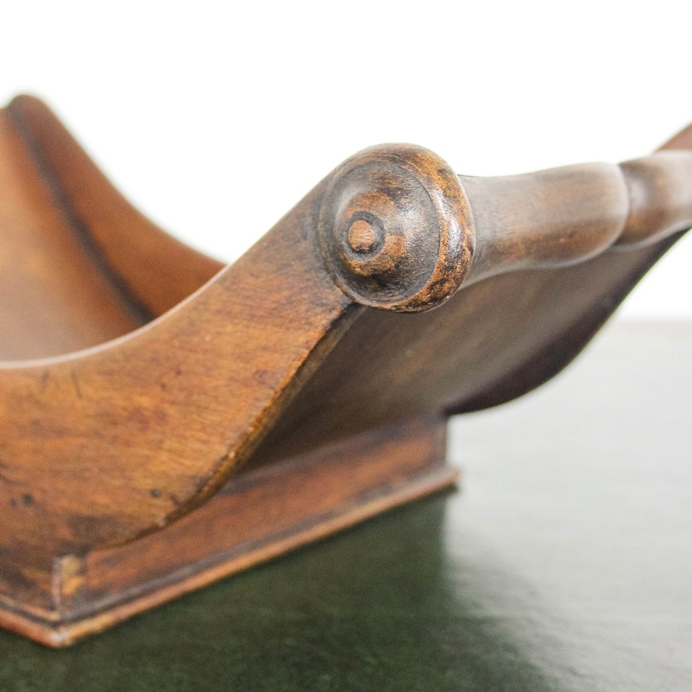 A Georgian mahogany cheese coaster featuring a curved trough with turned scroll ends resting on a rectangular base. View IV