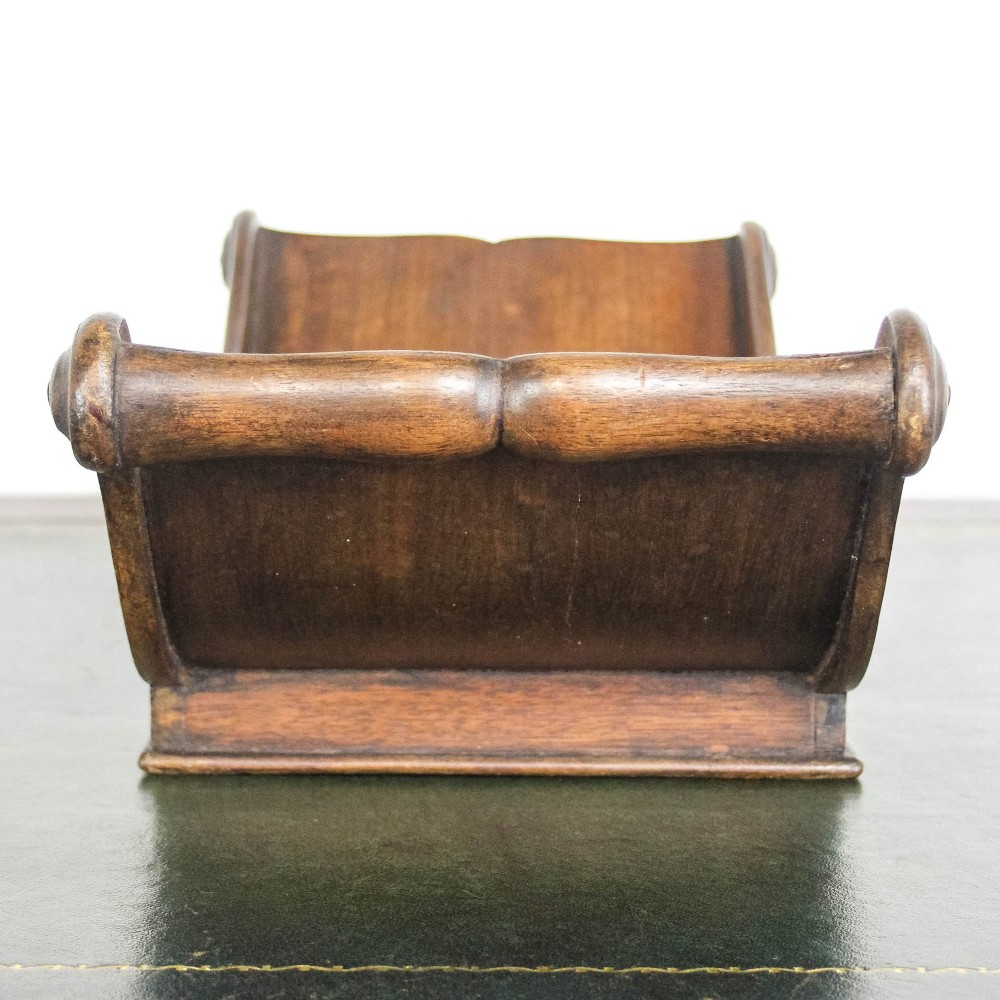 A Georgian mahogany cheese coaster featuring a curved trough with turned scroll ends resting on a rectangular base. View V