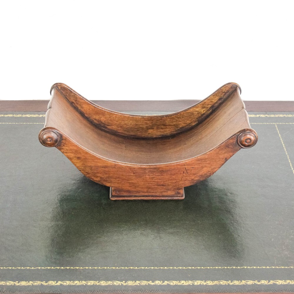 A Georgian mahogany cheese coaster featuring a curved trough with turned scroll ends resting on a rectangular base. View VIII