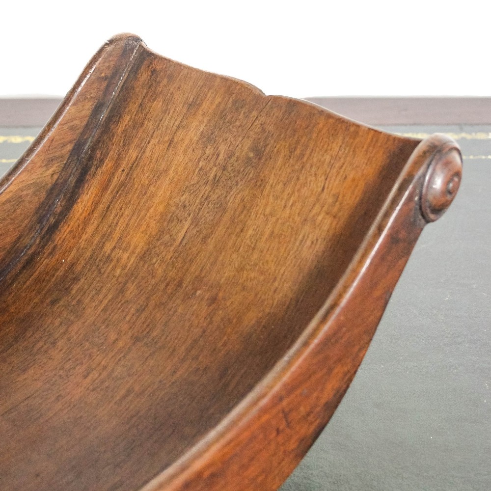 A Georgian mahogany cheese coaster featuring a curved trough with turned scroll ends resting on a rectangular base. View XI