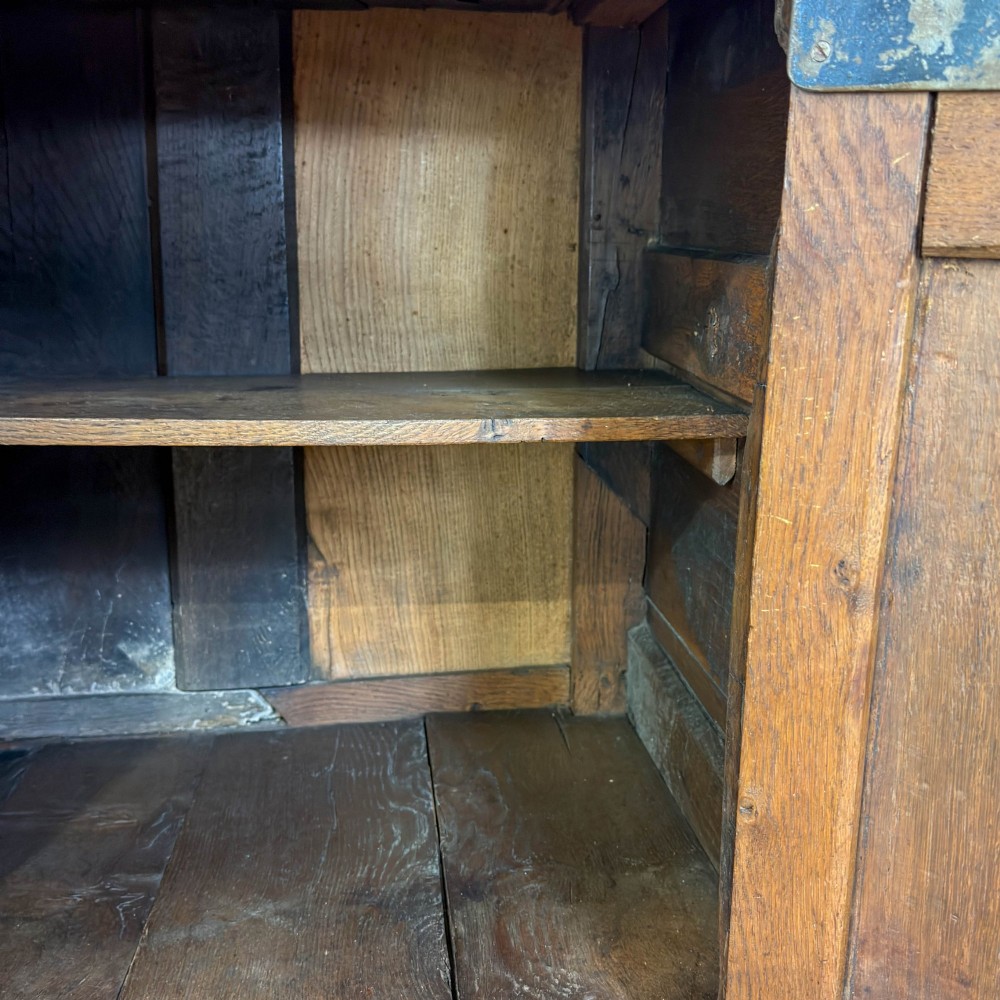An antique Georgian oak dresser base with multiple drawers, fielded panel cupboard doors, and brass swan-neck handles on a bracket feet base. View III