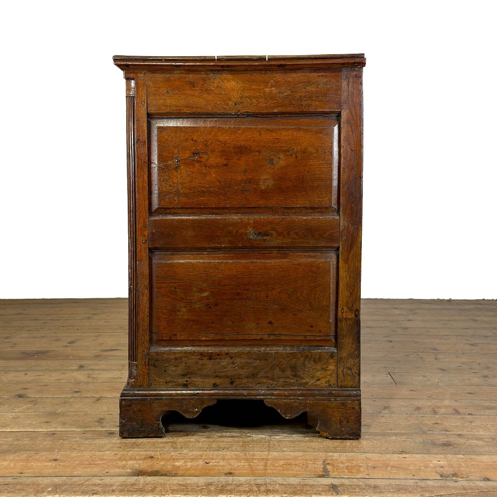 An antique Georgian oak dresser base with multiple drawers, fielded panel cupboard doors, and brass swan-neck handles on a bracket feet base. View VII