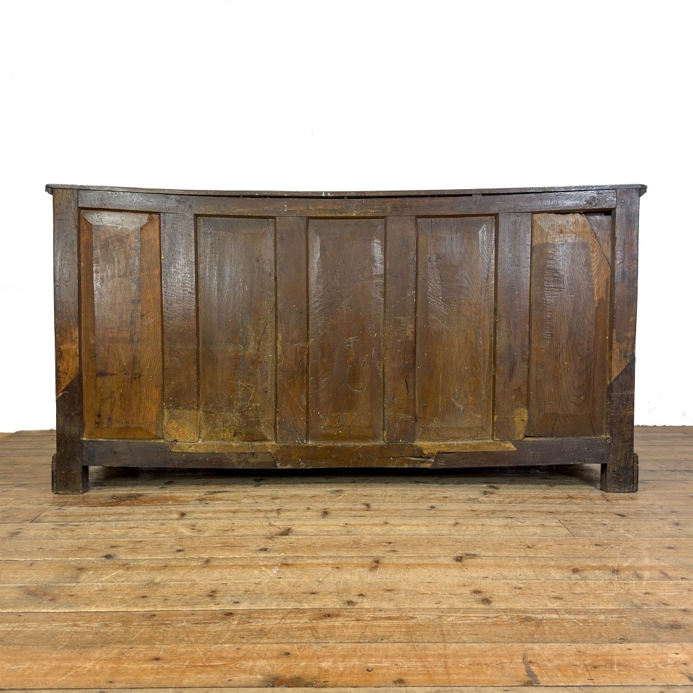 An antique Georgian oak dresser base with multiple drawers, fielded panel cupboard doors, and brass swan-neck handles on a bracket feet base. View X