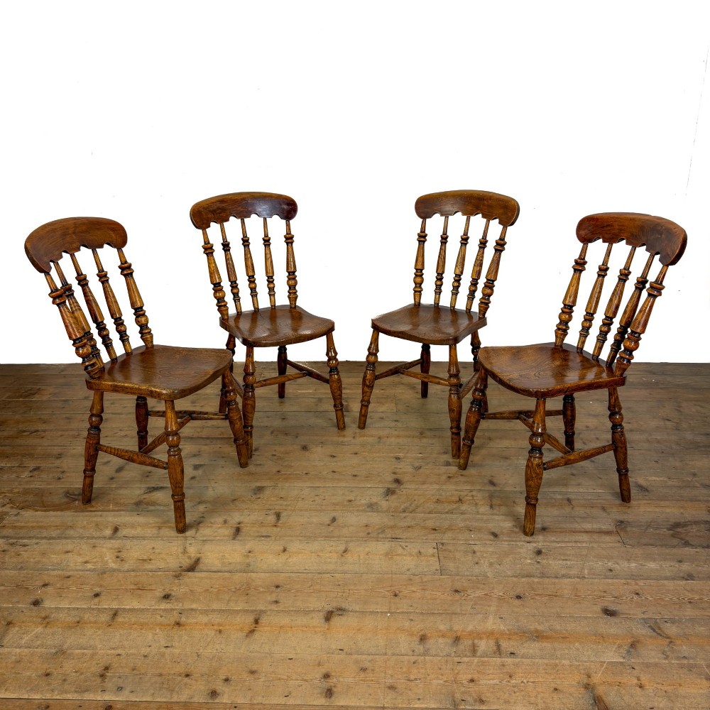 A matching set of four wooden farmhouse kitchen chairs featuring turned spindle backs, contoured seats, and turned legs connected by H-stretchers. View II