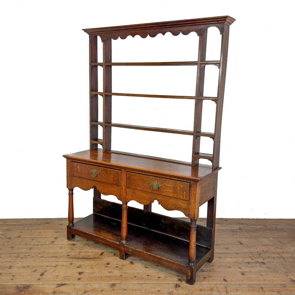 An antique oak Welsh dresser featuring an open tiered plate rack with a scalloped top frieze over two drawers and a bottom pot board shelf. View III
