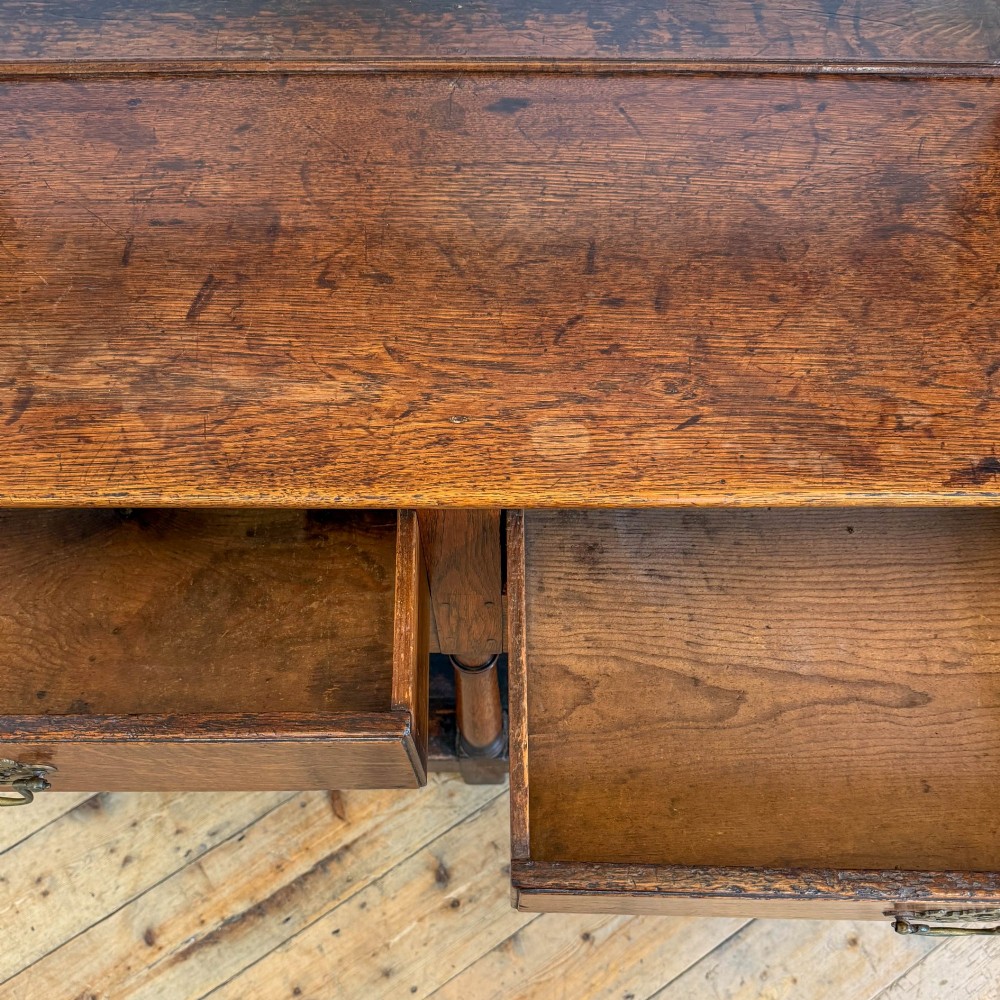 An antique oak Welsh dresser featuring an open tiered plate rack with a scalloped top frieze over two drawers and a bottom pot board shelf. View V