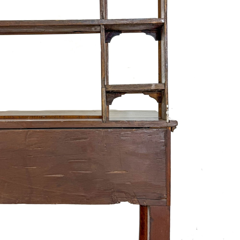 An antique oak Welsh dresser featuring an open tiered plate rack with a scalloped top frieze over two drawers and a bottom pot board shelf. View VIII