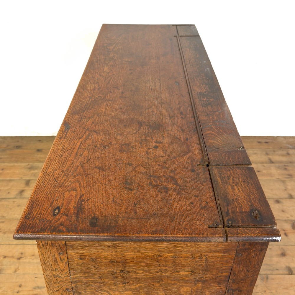 An antique oak dresser base featuring two drawers with brass backplate handles, shaped lower aprons, turned front legs, and an open potboard shelf. View IV
