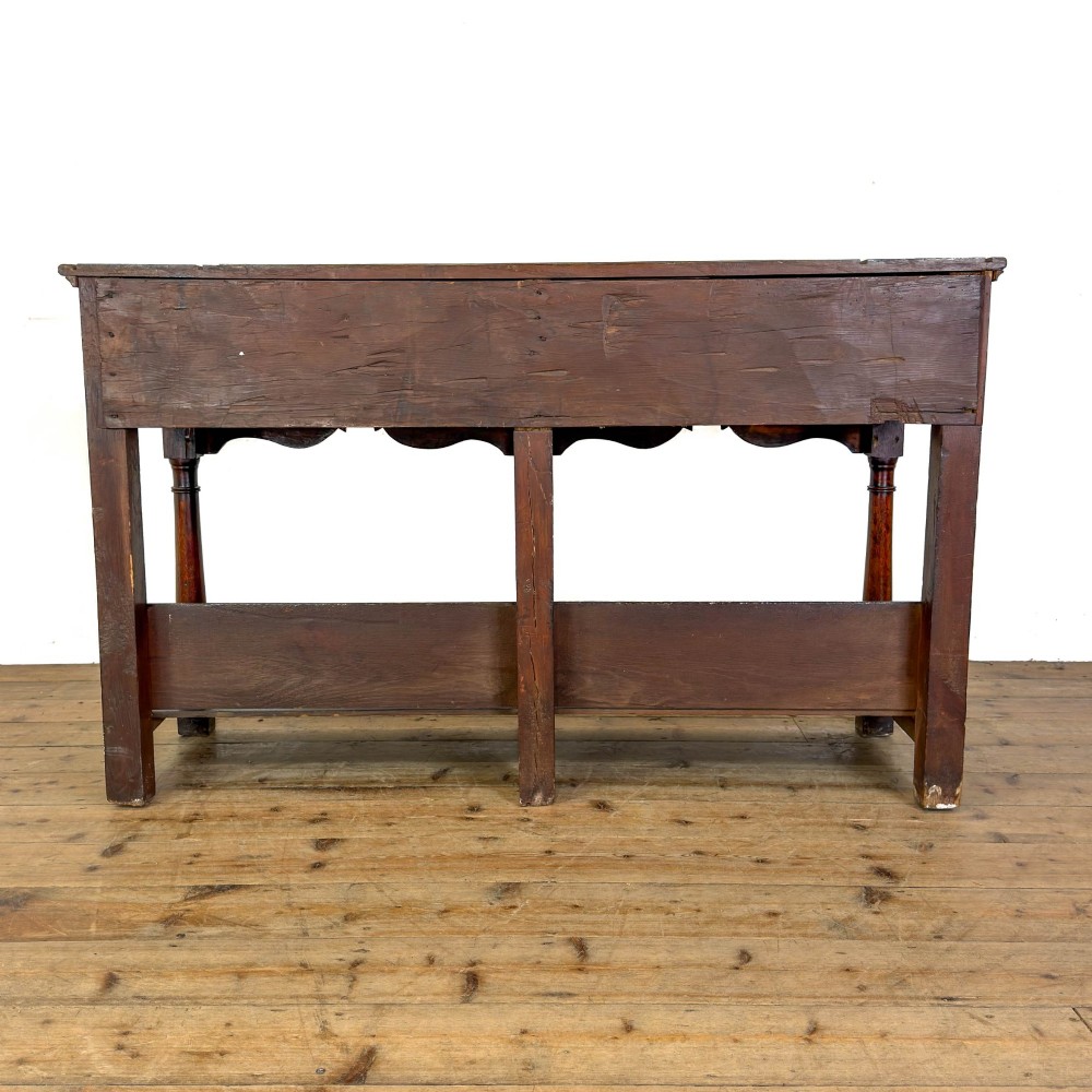 An antique oak dresser base featuring two drawers with brass backplate handles, shaped lower aprons, turned front legs, and an open potboard shelf. View VII