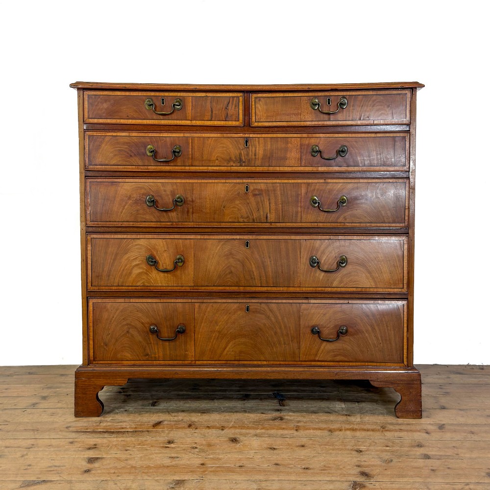A Georgian mahogany chest of drawers featuring two short over four long graduated drawers with brass swan-neck handles and bracket feet.