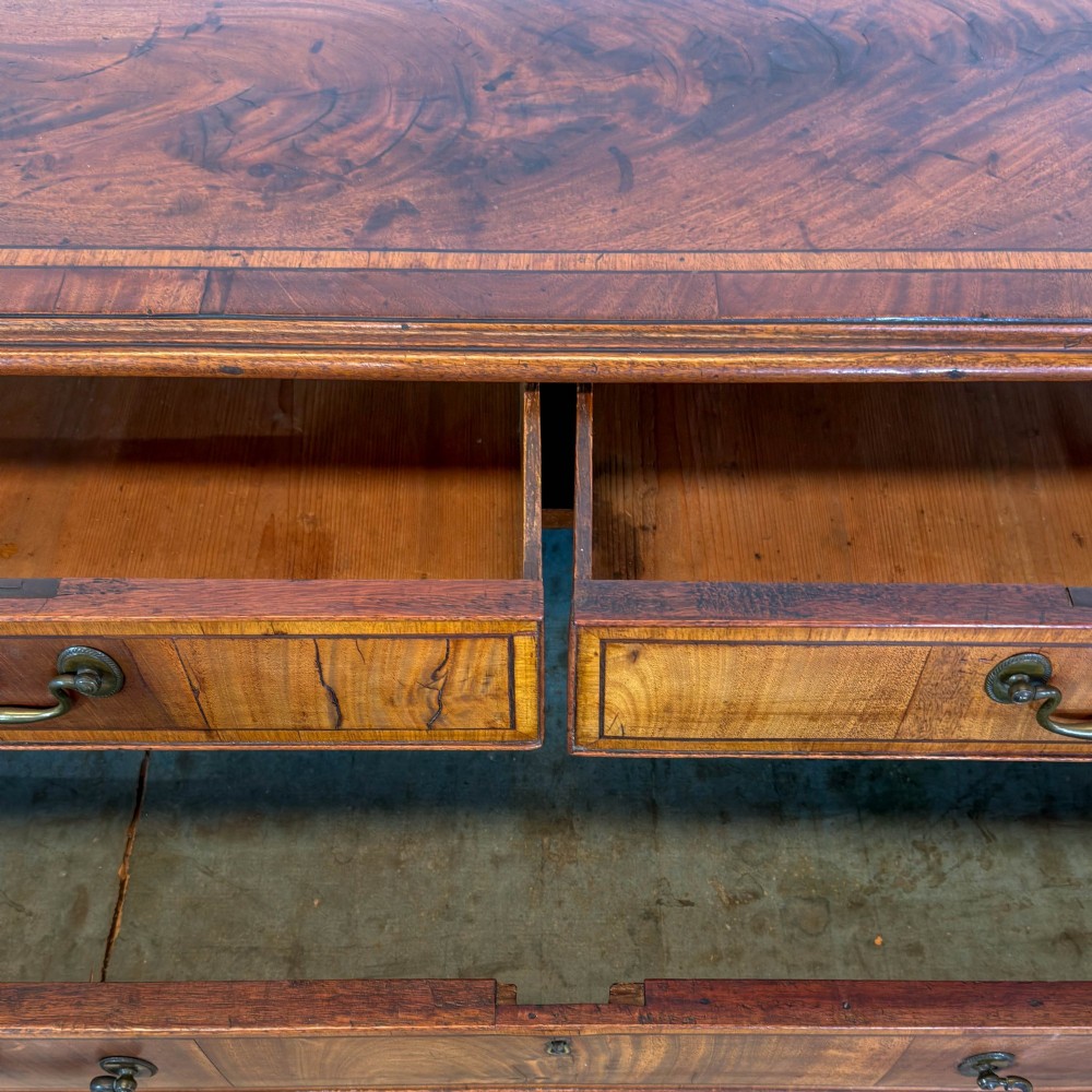 A Georgian mahogany chest of drawers featuring two short over four long graduated drawers with brass swan-neck handles and bracket feet. View II