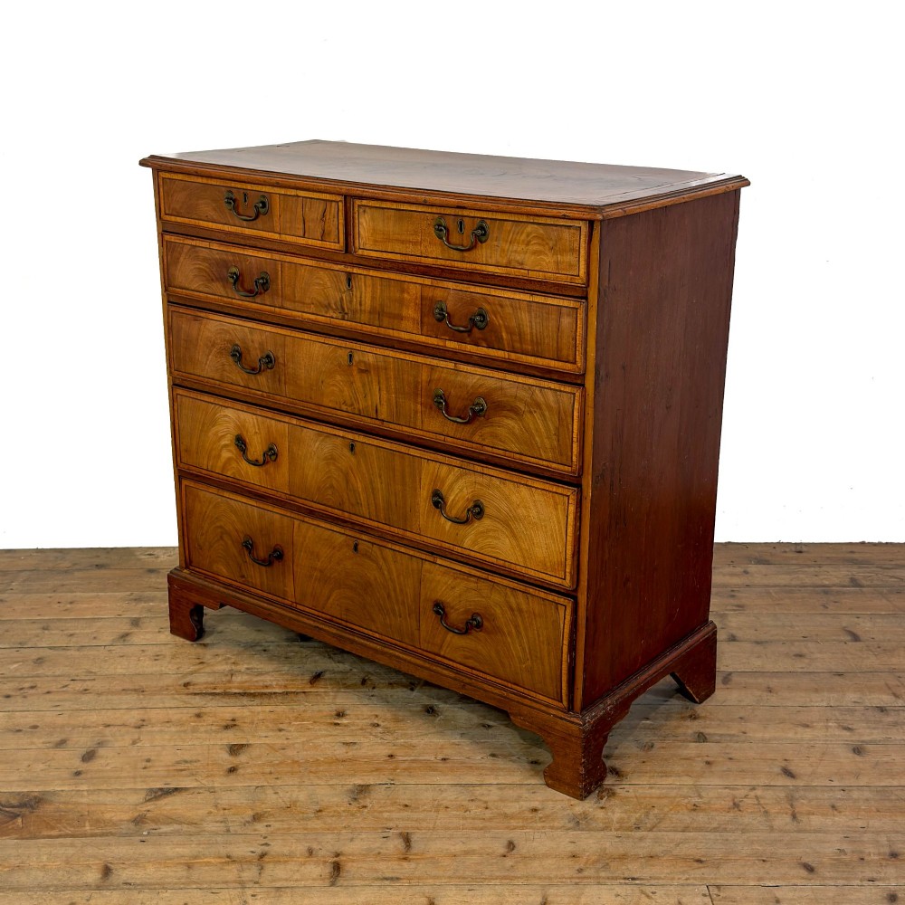 A Georgian mahogany chest of drawers featuring two short over four long graduated drawers with brass swan-neck handles and bracket feet. View IV