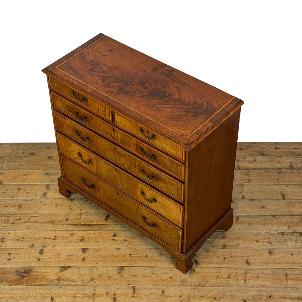 A Georgian mahogany chest of drawers featuring two short over four long graduated drawers with brass swan-neck handles and bracket feet. View V
