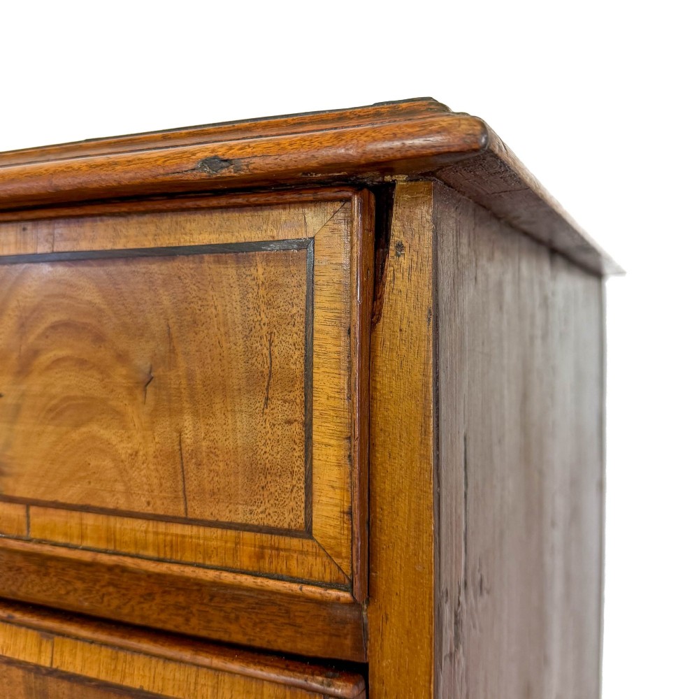 A Georgian mahogany chest of drawers featuring two short over four long graduated drawers with brass swan-neck handles and bracket feet. View VI