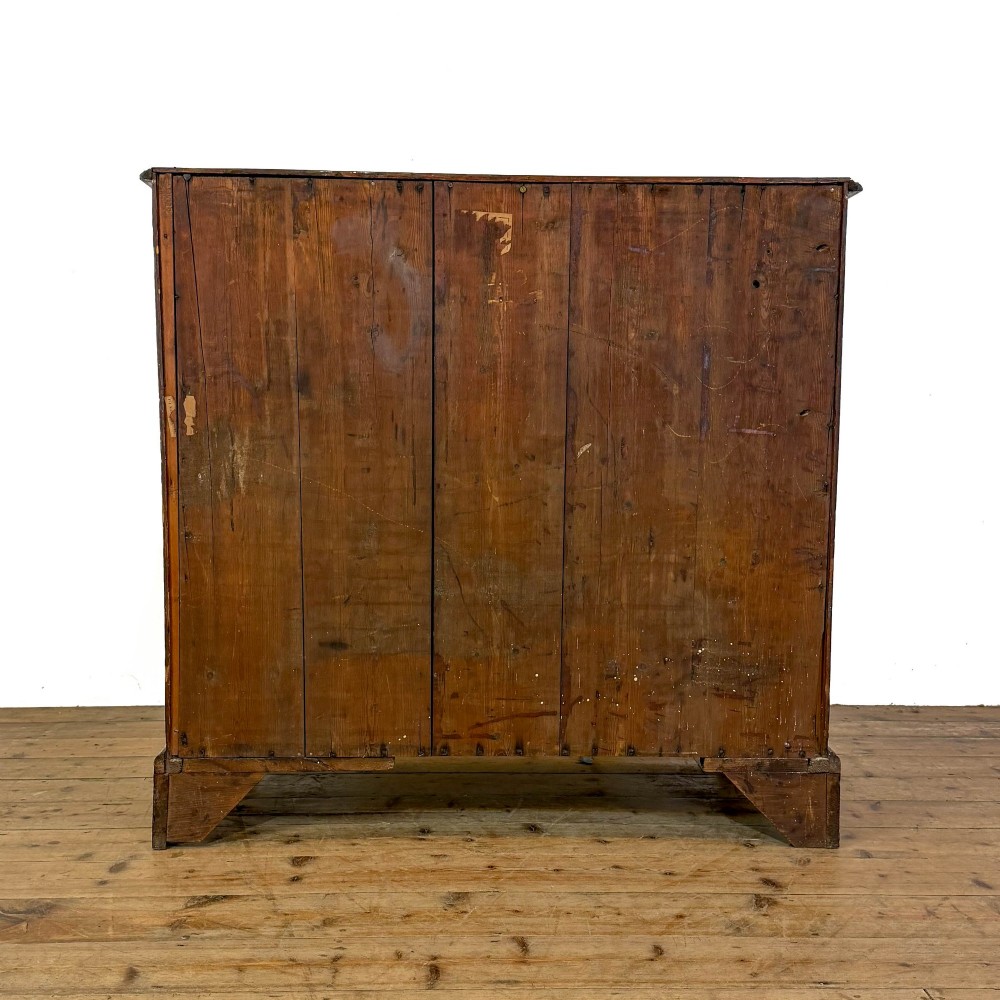 A Georgian mahogany chest of drawers featuring two short over four long graduated drawers with brass swan-neck handles and bracket feet. View IX
