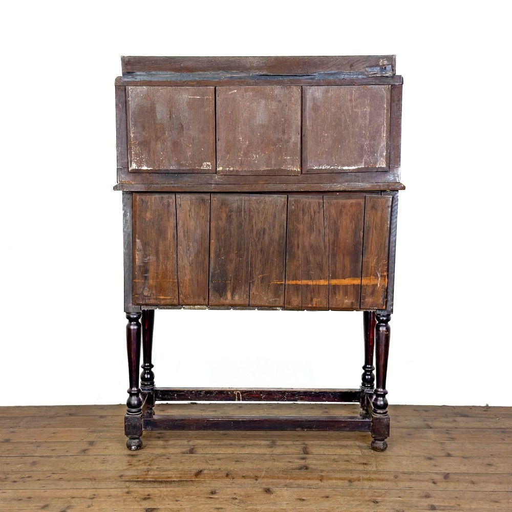 A dark carved oak Victorian sideboard with a tiered top shelf, detailed geometric carved door panels, brass hinges, and turned legs with a lower stretcher rail. View X