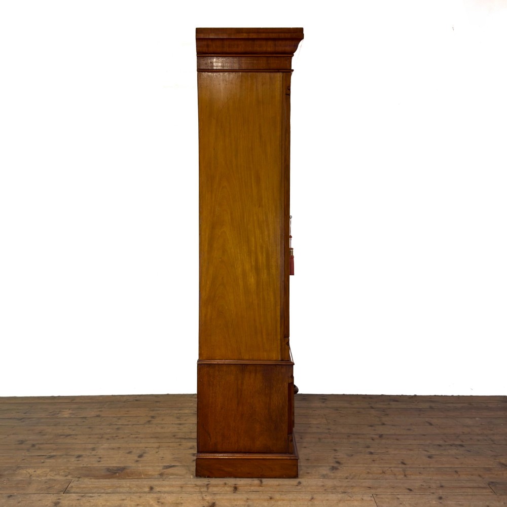A tall Victorian mahogany wardrobe featuring an arched central mirrored door flanked by wooden side panels over a wide base drawer. View III