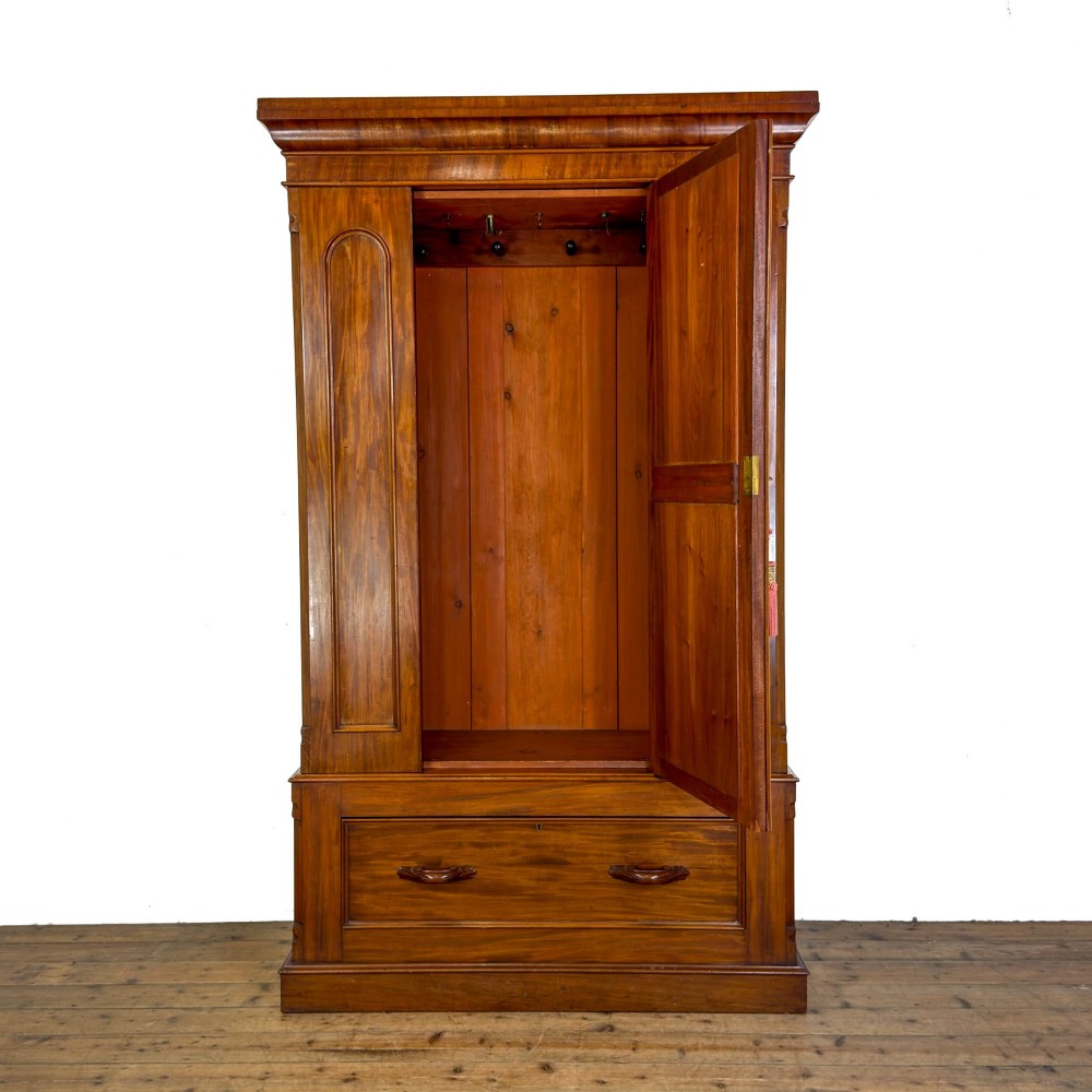 A tall Victorian mahogany wardrobe featuring an arched central mirrored door flanked by wooden side panels over a wide base drawer. View IV