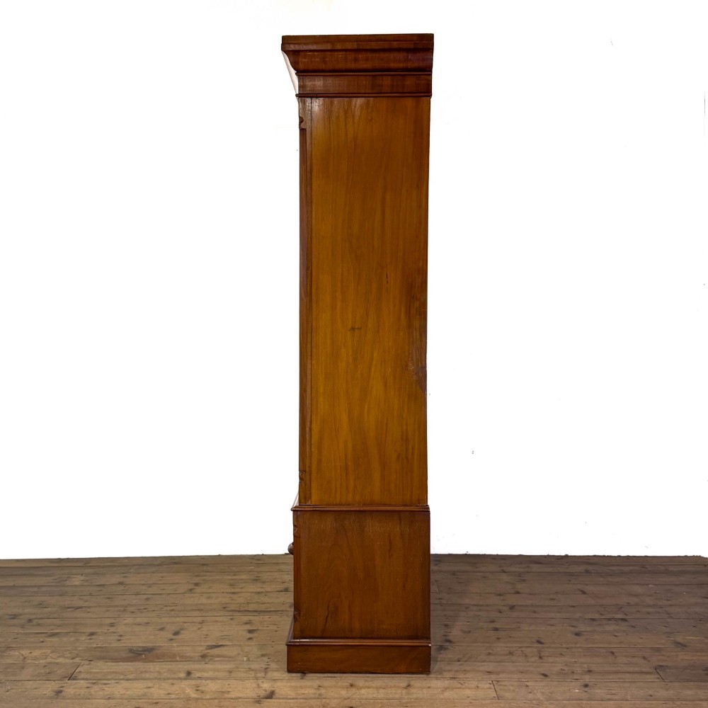 A tall Victorian mahogany wardrobe featuring an arched central mirrored door flanked by wooden side panels over a wide base drawer. View VIII