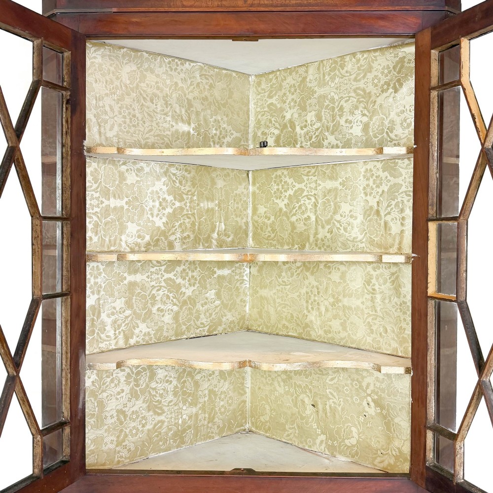 A tall two-part mahogany corner cabinet featuring geometric astragal glazed upper doors above panelled lower doors. View III