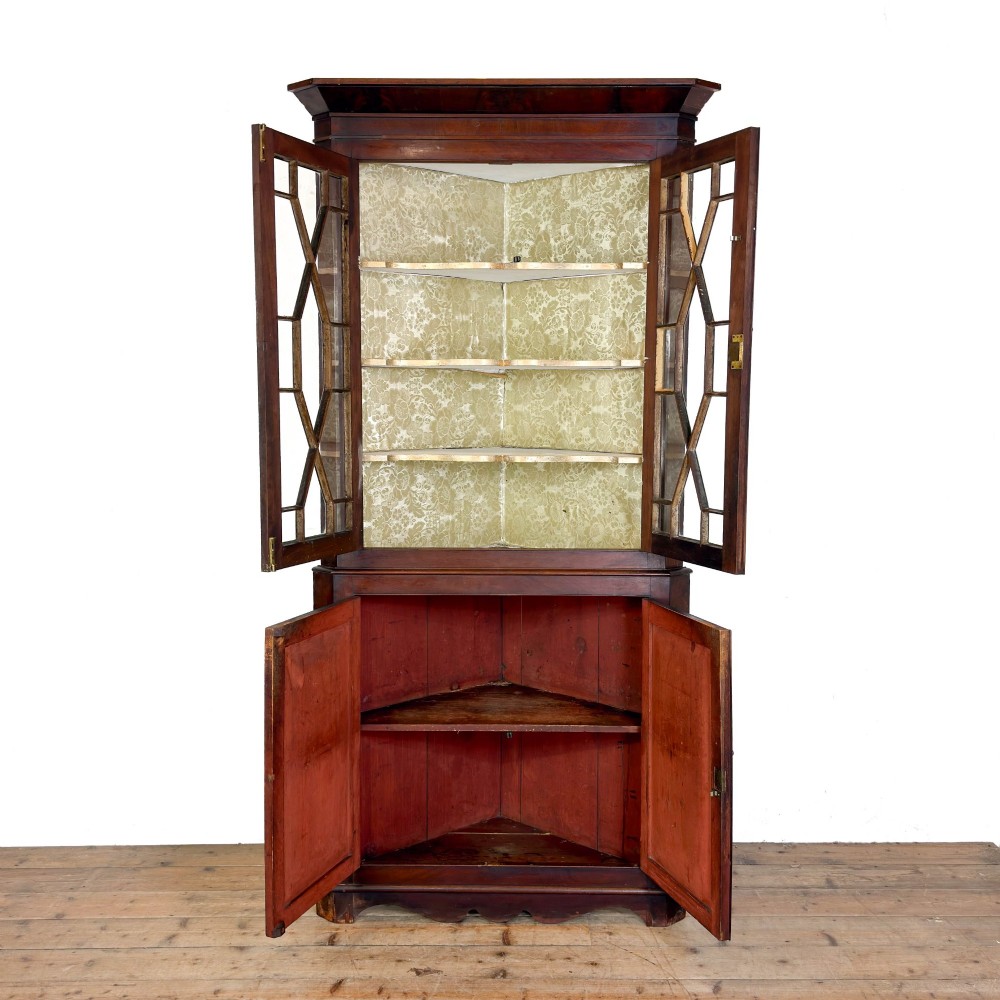 A tall two-part mahogany corner cabinet featuring geometric astragal glazed upper doors above panelled lower doors. View IV