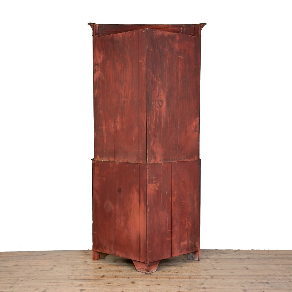 A tall two-part mahogany corner cabinet featuring geometric astragal glazed upper doors above panelled lower doors. View VII