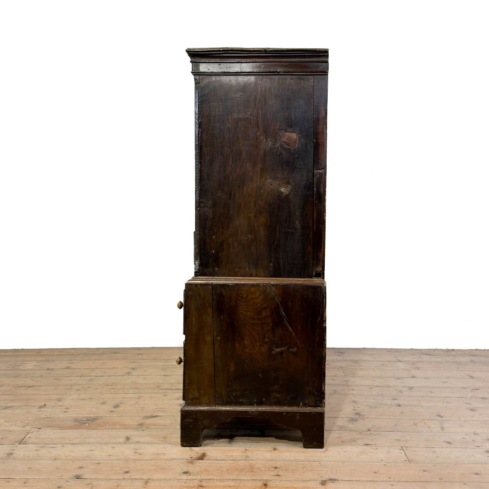 An 18th-century Welsh dark oak Carmarthenshire coffer featuring upper cupboard doors with pointed arch fielded panels above multiple drawers fitted with brass knobs. View IV