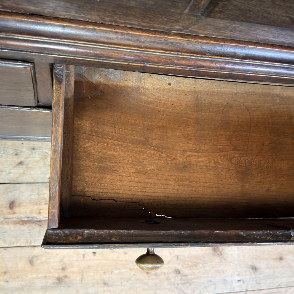 An 18th-century Welsh dark oak Carmarthenshire coffer featuring upper cupboard doors with pointed arch fielded panels above multiple drawers fitted with brass knobs. View X