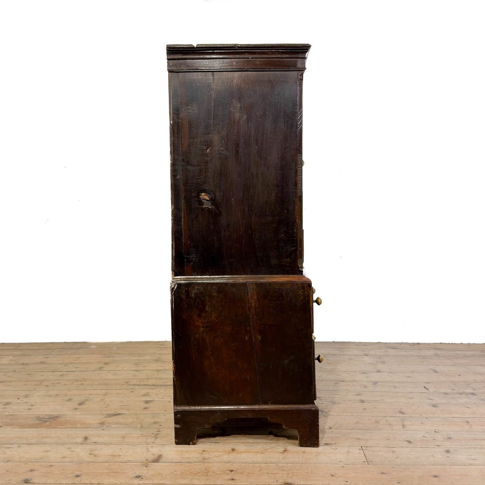 An 18th-century Welsh dark oak Carmarthenshire coffer featuring upper cupboard doors with pointed arch fielded panels above multiple drawers fitted with brass knobs. View XI