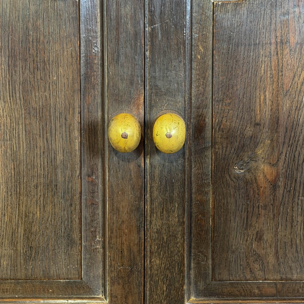 An 18th-century Welsh dark oak Carmarthenshire coffer featuring upper cupboard doors with pointed arch fielded panels above multiple drawers fitted with brass knobs. View XIII