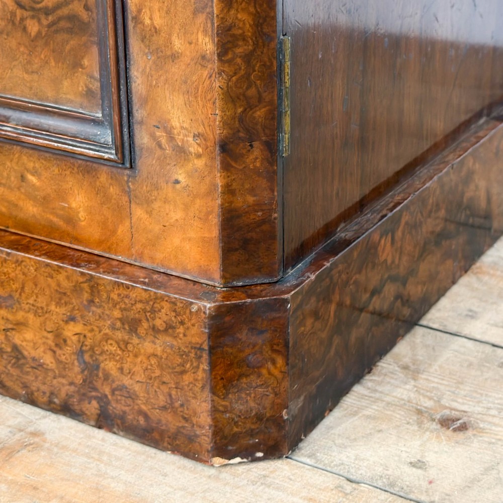 A Victorian burr walnut pot cupboard featuring a single panelled door with a turned wooden knob, chamfered corners, and a solid plinth base. View V