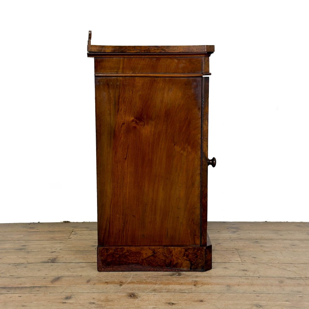 A Victorian burr walnut pot cupboard featuring a single panelled door with a turned wooden knob, chamfered corners, and a solid plinth base. View VII