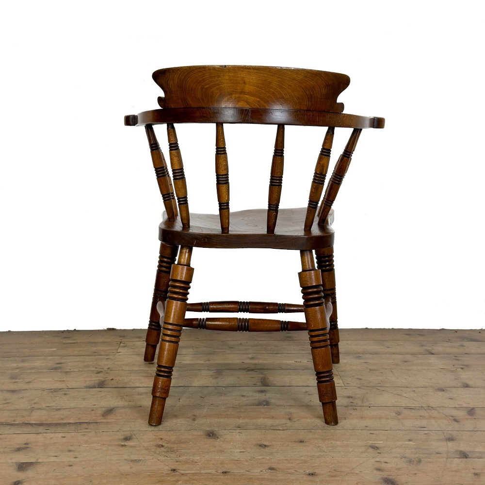 A warm brown wooden smokers bow armchair featuring turned legs, vertical back spindles, a steam-bent curved top rail, and a shaped solid seat. View IV
