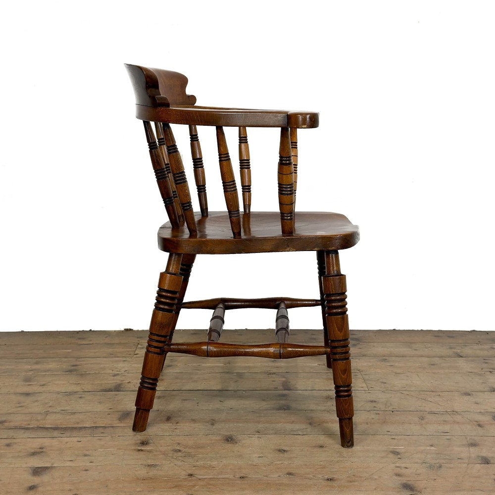 A warm brown wooden smokers bow armchair featuring turned legs, vertical back spindles, a steam-bent curved top rail, and a shaped solid seat. View V