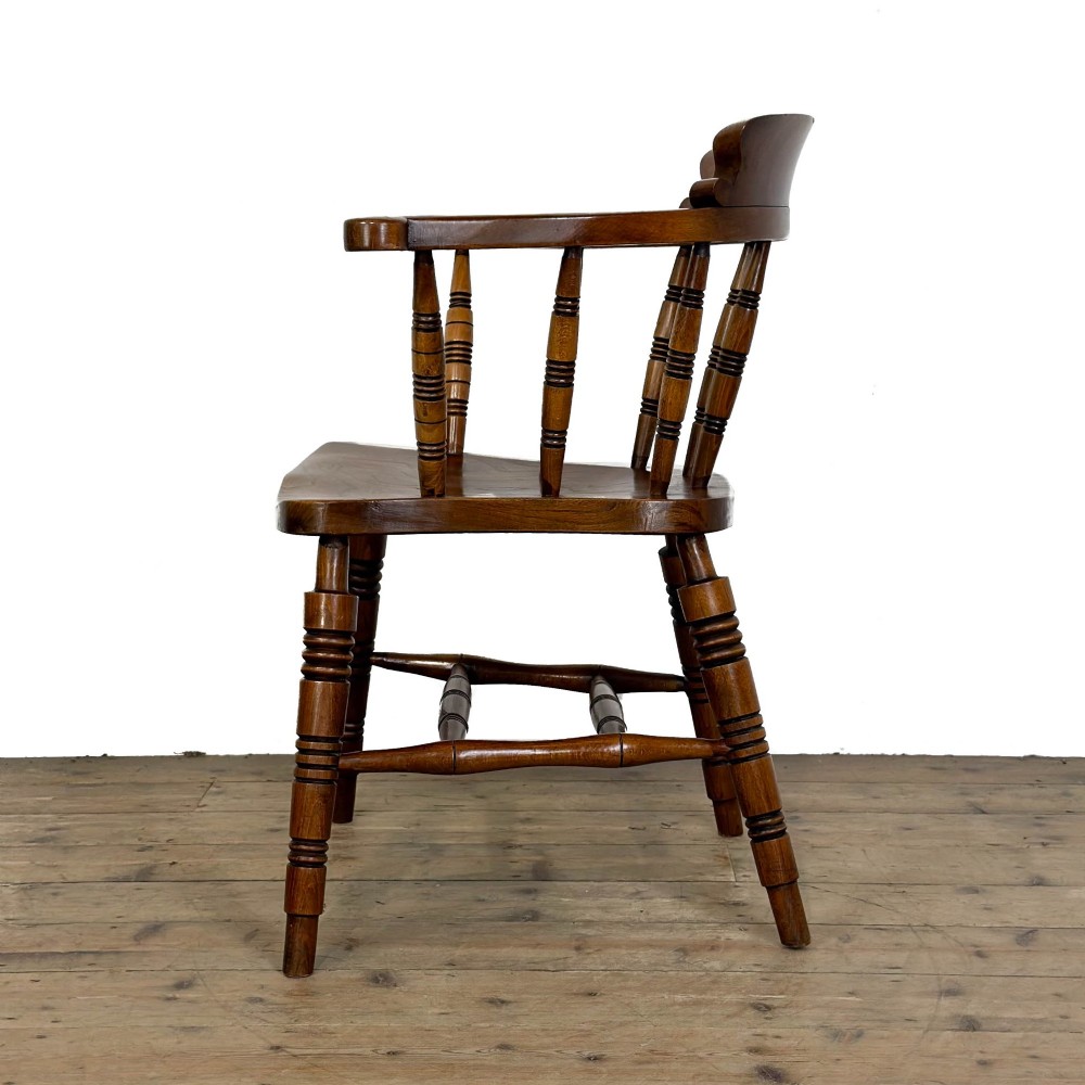 A warm brown wooden smokers bow armchair featuring turned legs, vertical back spindles, a steam-bent curved top rail, and a shaped solid seat. View VI