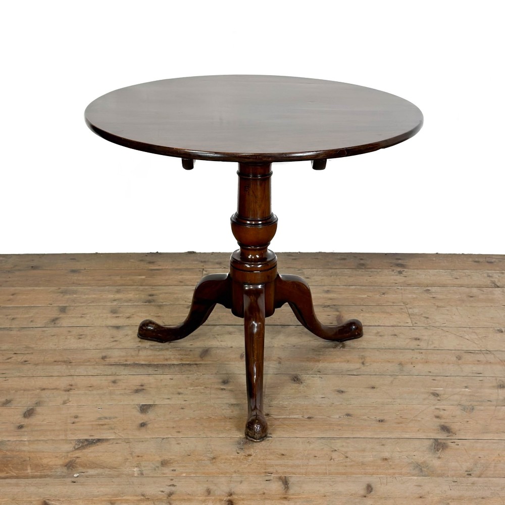 An antique mahogany tilt-top occasional table featuring a round circular top, turned central column pedestal, and three splayed cabriole legs with pad feet.
