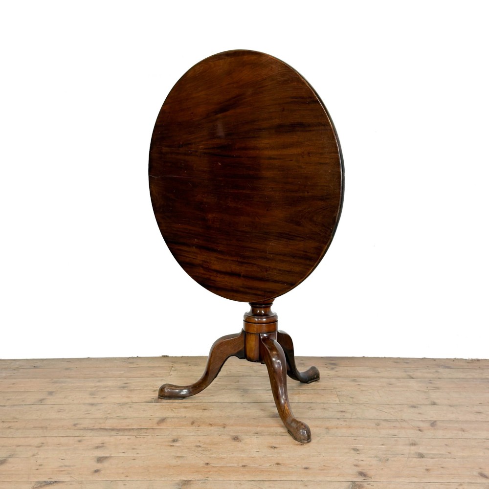 An antique mahogany tilt-top occasional table featuring a round circular top, turned central column pedestal, and three splayed cabriole legs with pad feet. View IV