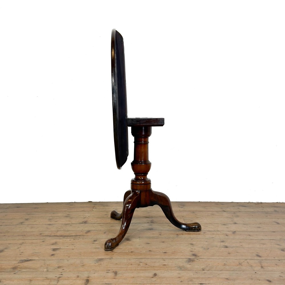 An antique mahogany tilt-top occasional table featuring a round circular top, turned central column pedestal, and three splayed cabriole legs with pad feet. View V
