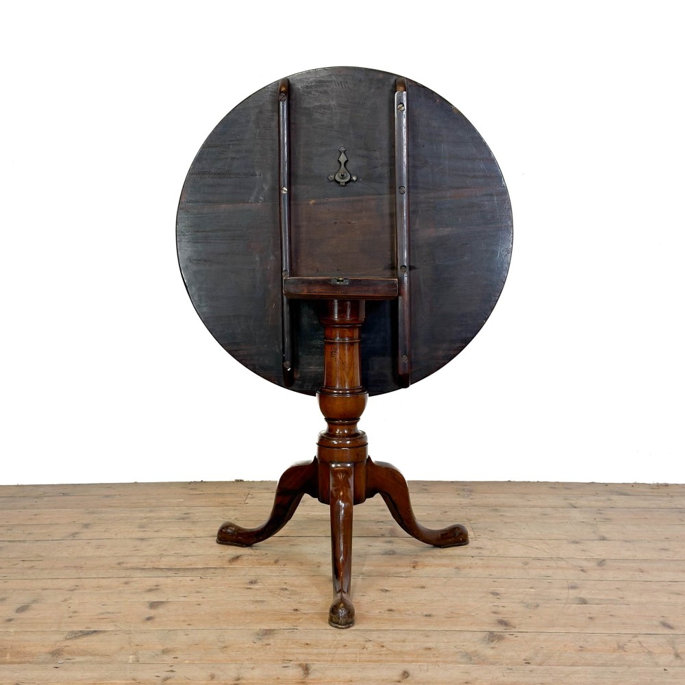 An antique mahogany tilt-top occasional table featuring a round circular top, turned central column pedestal, and three splayed cabriole legs with pad feet. View VI