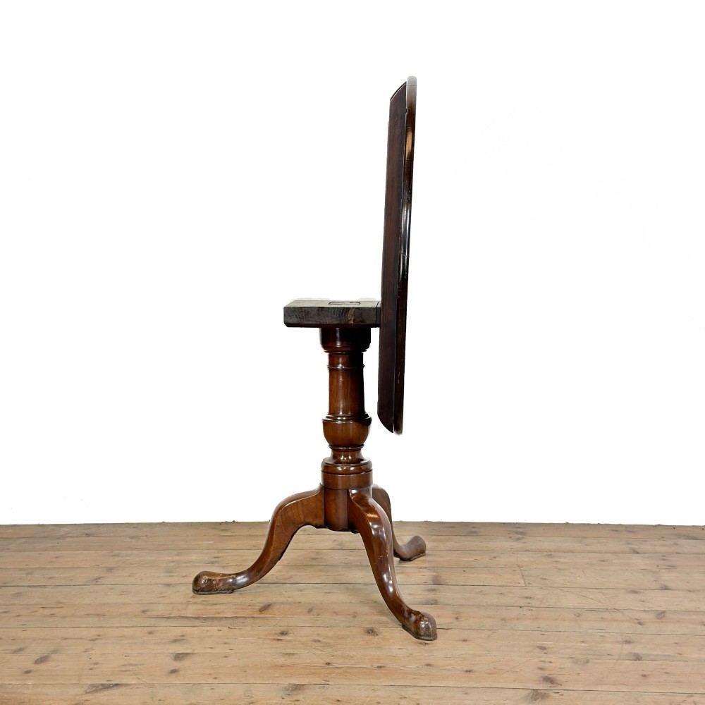 An antique mahogany tilt-top occasional table featuring a round circular top, turned central column pedestal, and three splayed cabriole legs with pad feet. View VIII