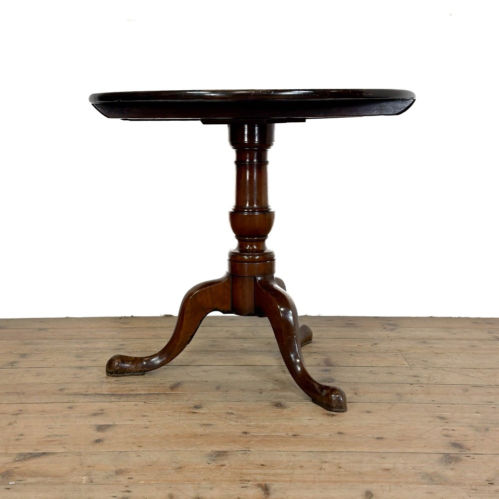 An antique mahogany tilt-top occasional table featuring a round circular top, turned central column pedestal, and three splayed cabriole legs with pad feet. View IX