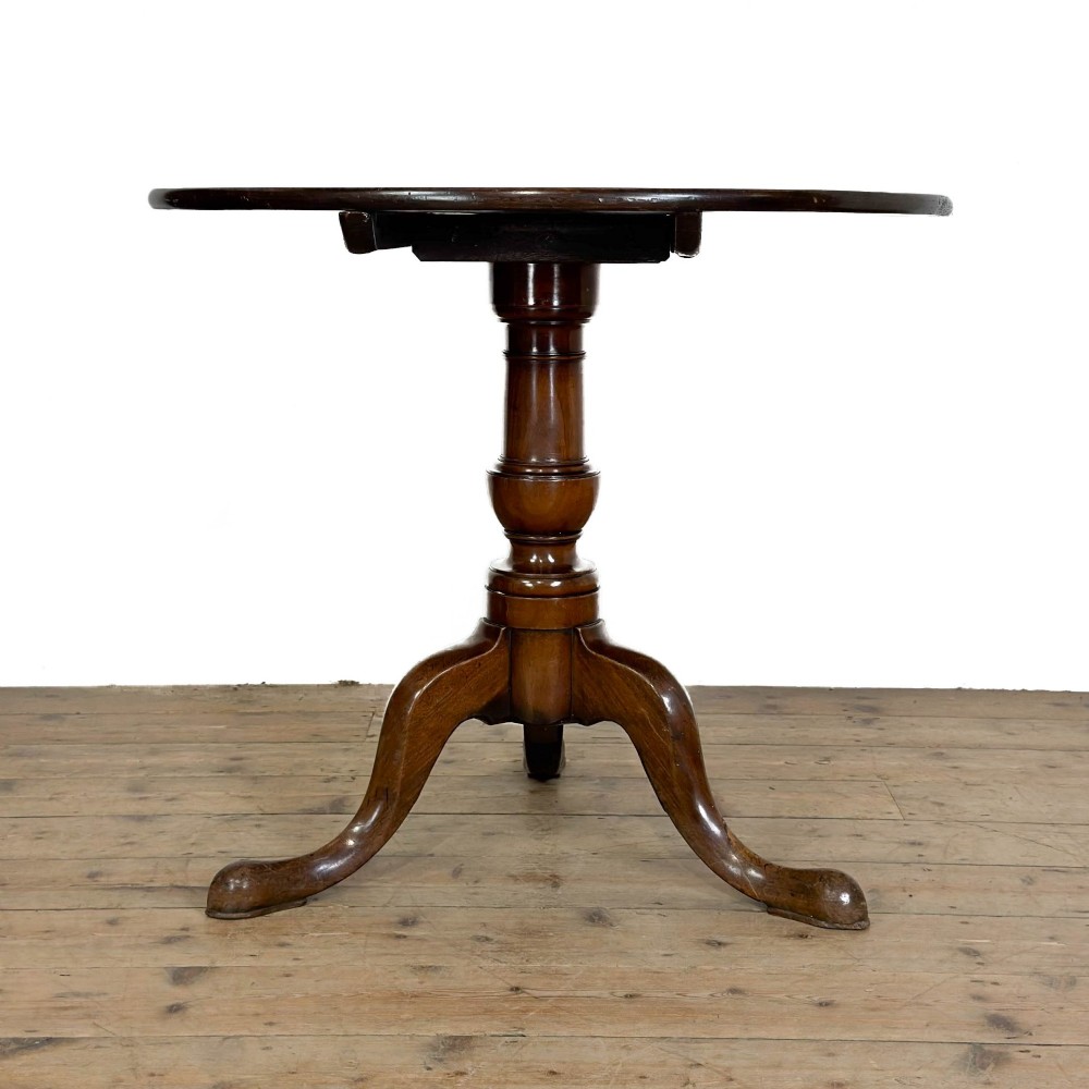 An antique mahogany tilt-top occasional table featuring a round circular top, turned central column pedestal, and three splayed cabriole legs with pad feet. View X