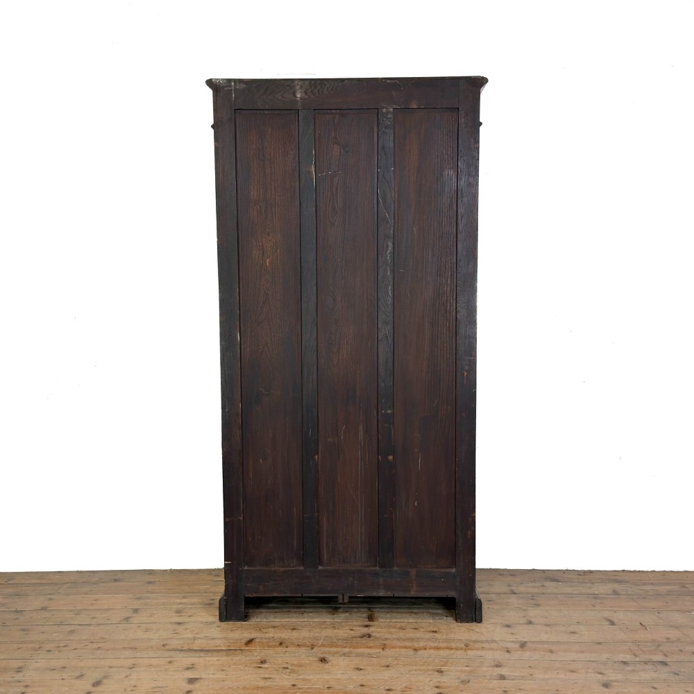 A tall dark oak open bookcase with multiple shelves, featuring carved floral scrollwork along the top frieze and fluted side columns. View VI