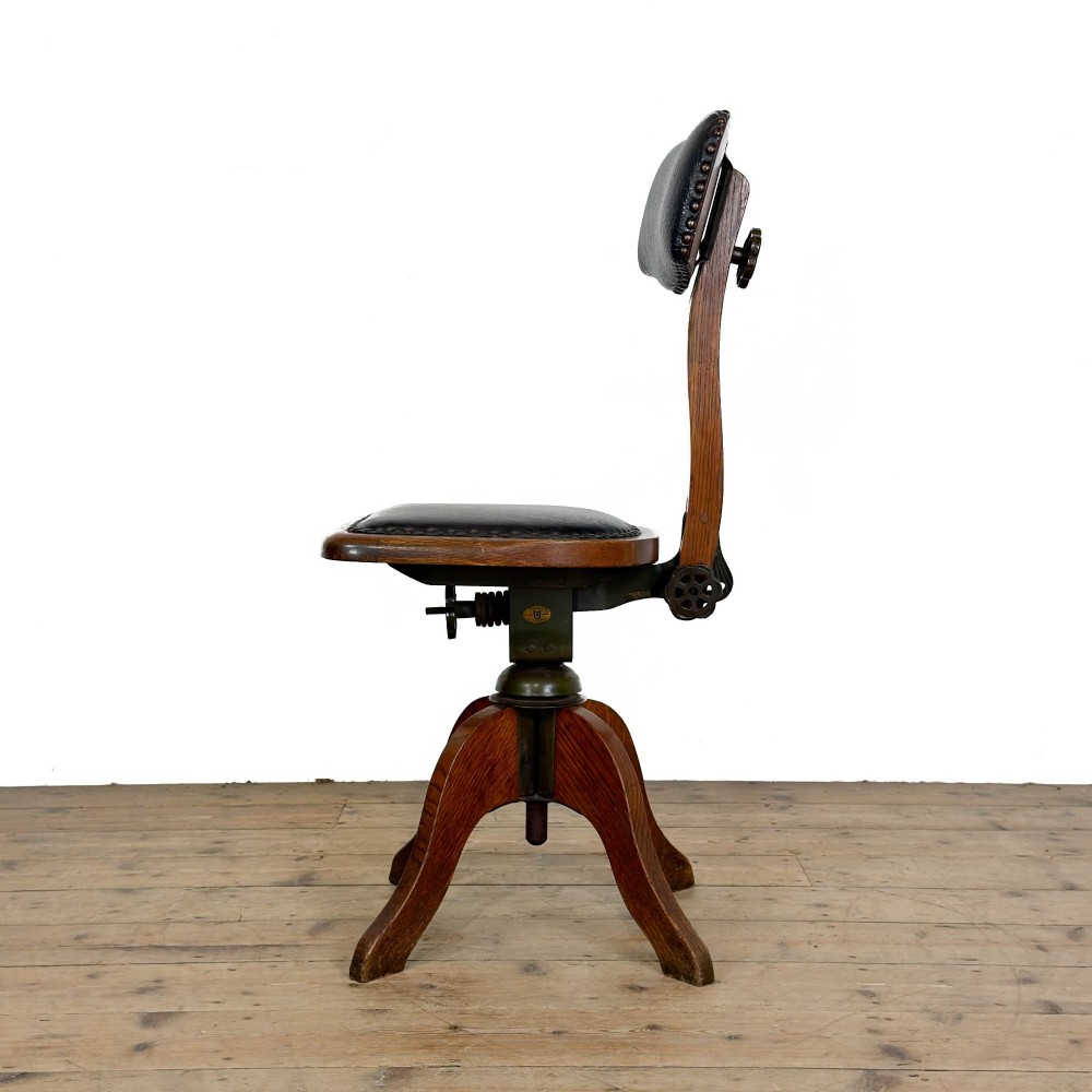 An early 20th-century oak swivel desk chair featuring dark studded leather upholstery, a curved lumbar backrest, and a four-star wooden base. View II