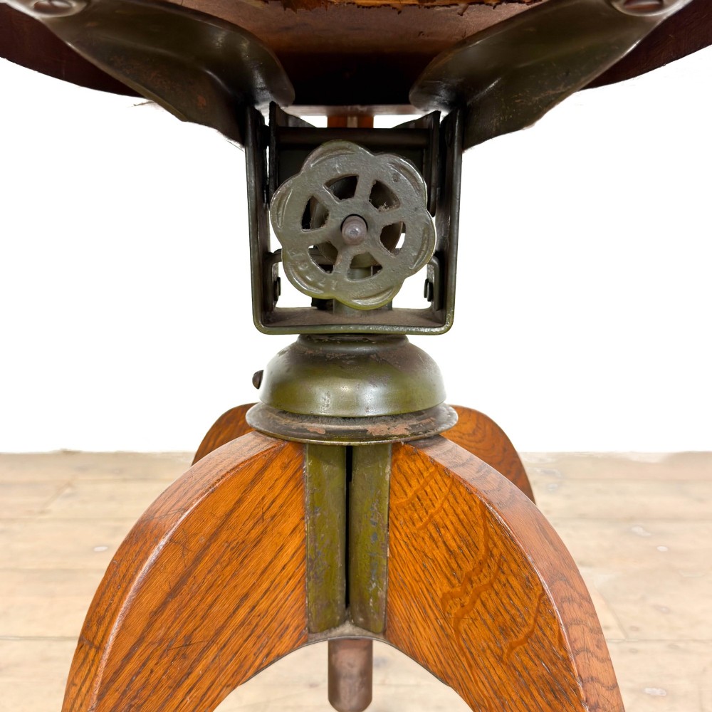 An early 20th-century oak swivel desk chair featuring dark studded leather upholstery, a curved lumbar backrest, and a four-star wooden base. View VIII