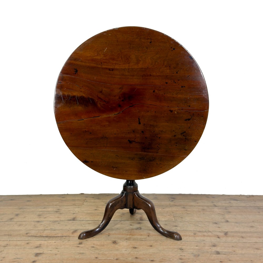 An antique George III mahogany tripod table featuring a circular tilt top shown in the upright position above a turned column and three down-swept legs.