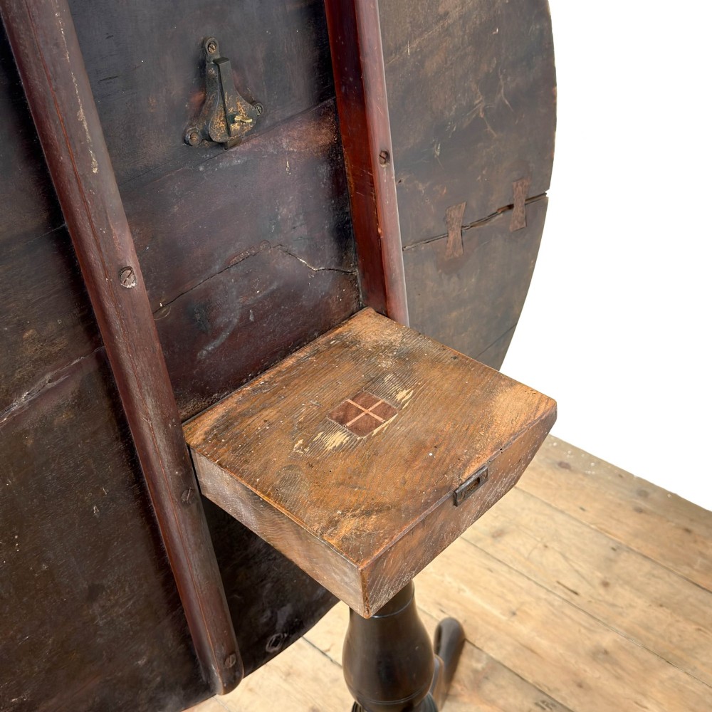 An antique George III mahogany tripod table featuring a circular tilt top shown in the upright position above a turned column and three down-swept legs. View II