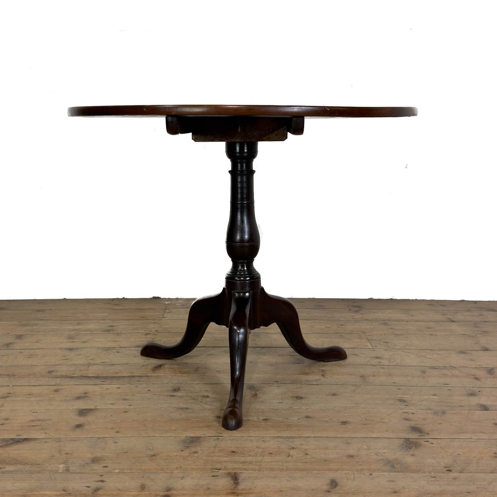 An antique George III mahogany tripod table featuring a circular tilt top shown in the upright position above a turned column and three down-swept legs. View III