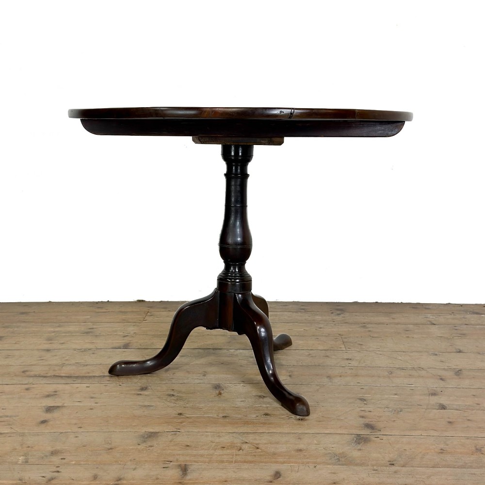 An antique George III mahogany tripod table featuring a circular tilt top shown in the upright position above a turned column and three down-swept legs. View IV