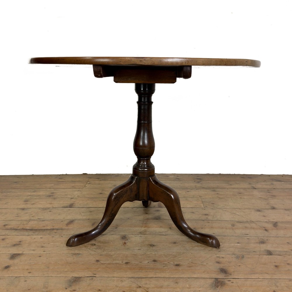 An antique George III mahogany tripod table featuring a circular tilt top shown in the upright position above a turned column and three down-swept legs. View V